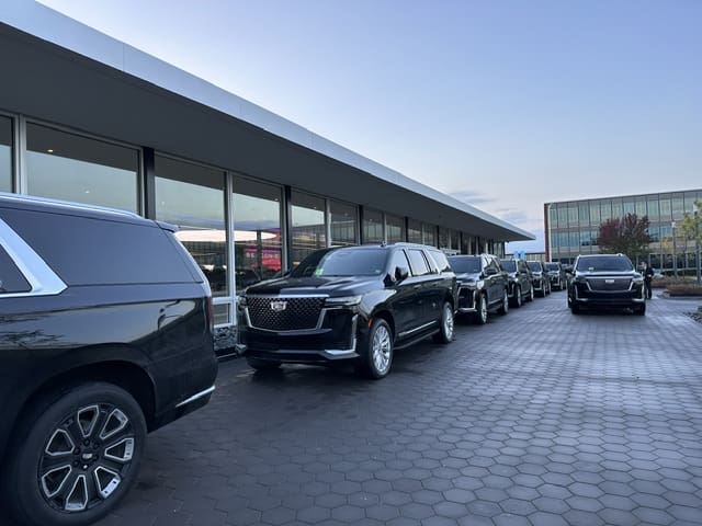 Row of black SUVs parked outside modern building